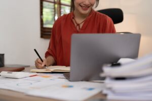 Asian Business woman writing saving account balance with working at home, account and saving concept